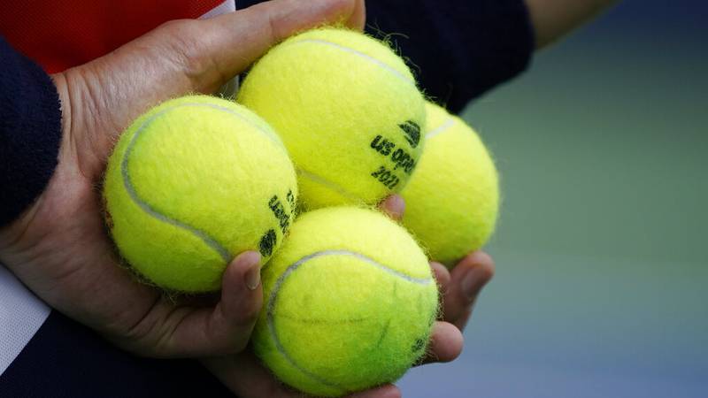A court attendant holds balls for service during the first round of the US Open tennis...